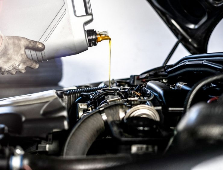 une personne qui verse de l'huile dans un moteur de voiture