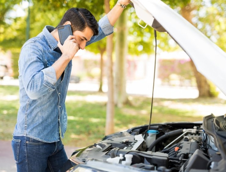 uomo al telefono controlla il vano motore per rumori auto