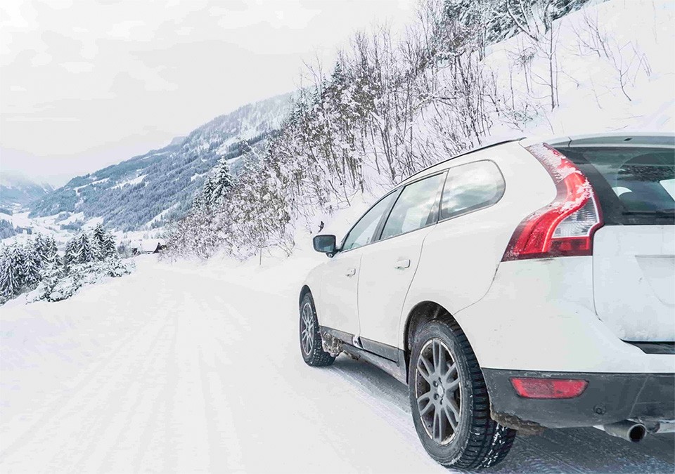une voiture blanche roulant sur une route enneigée